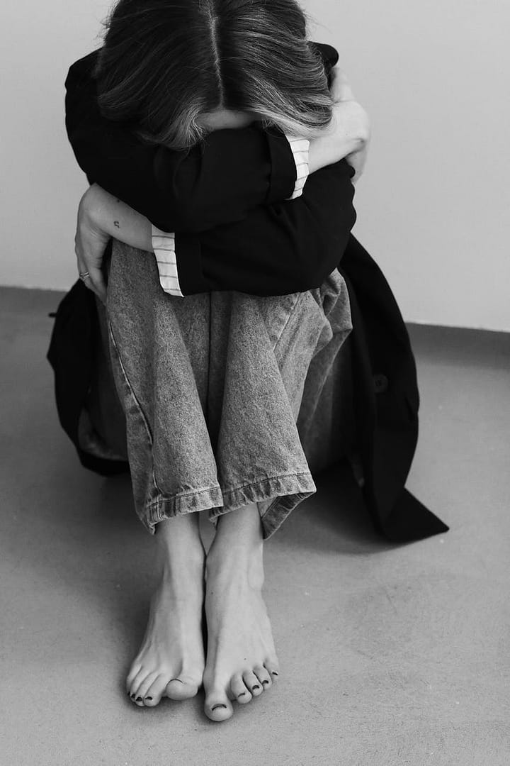 anonymous sad woman sitting on floor and embracing knees