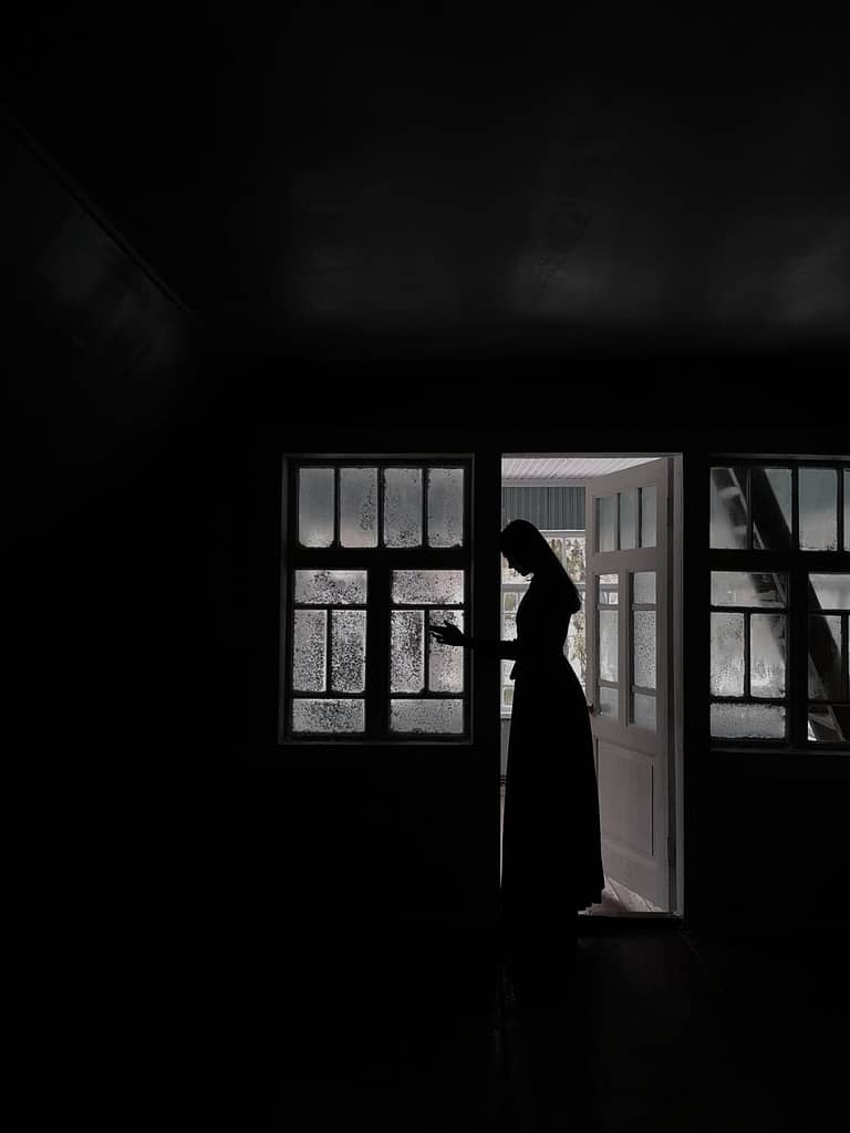 woman in long dress standing in doorway in house